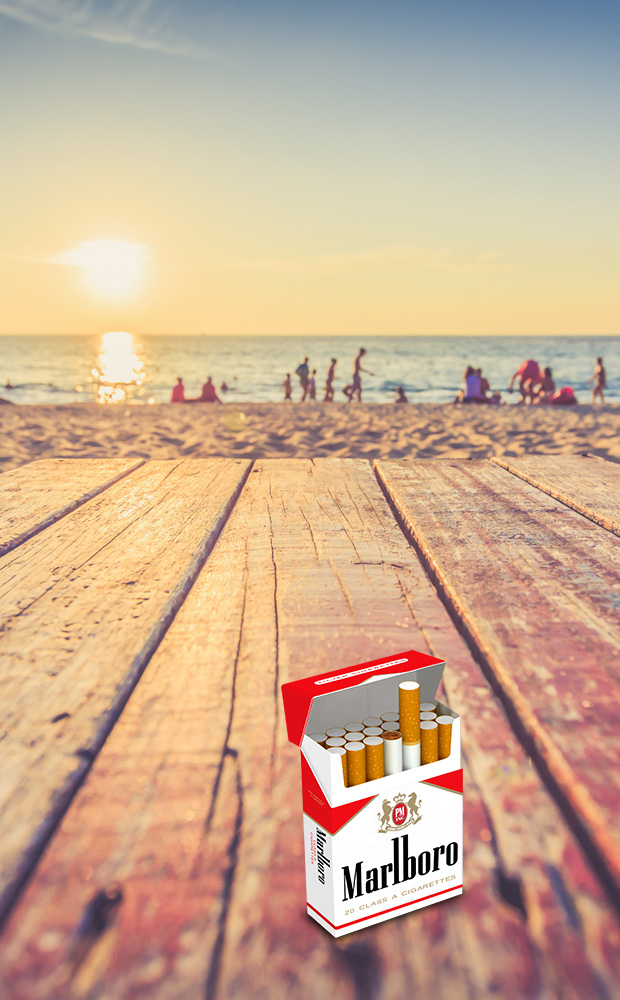 A red Malboro cigarette box on table in front of beach